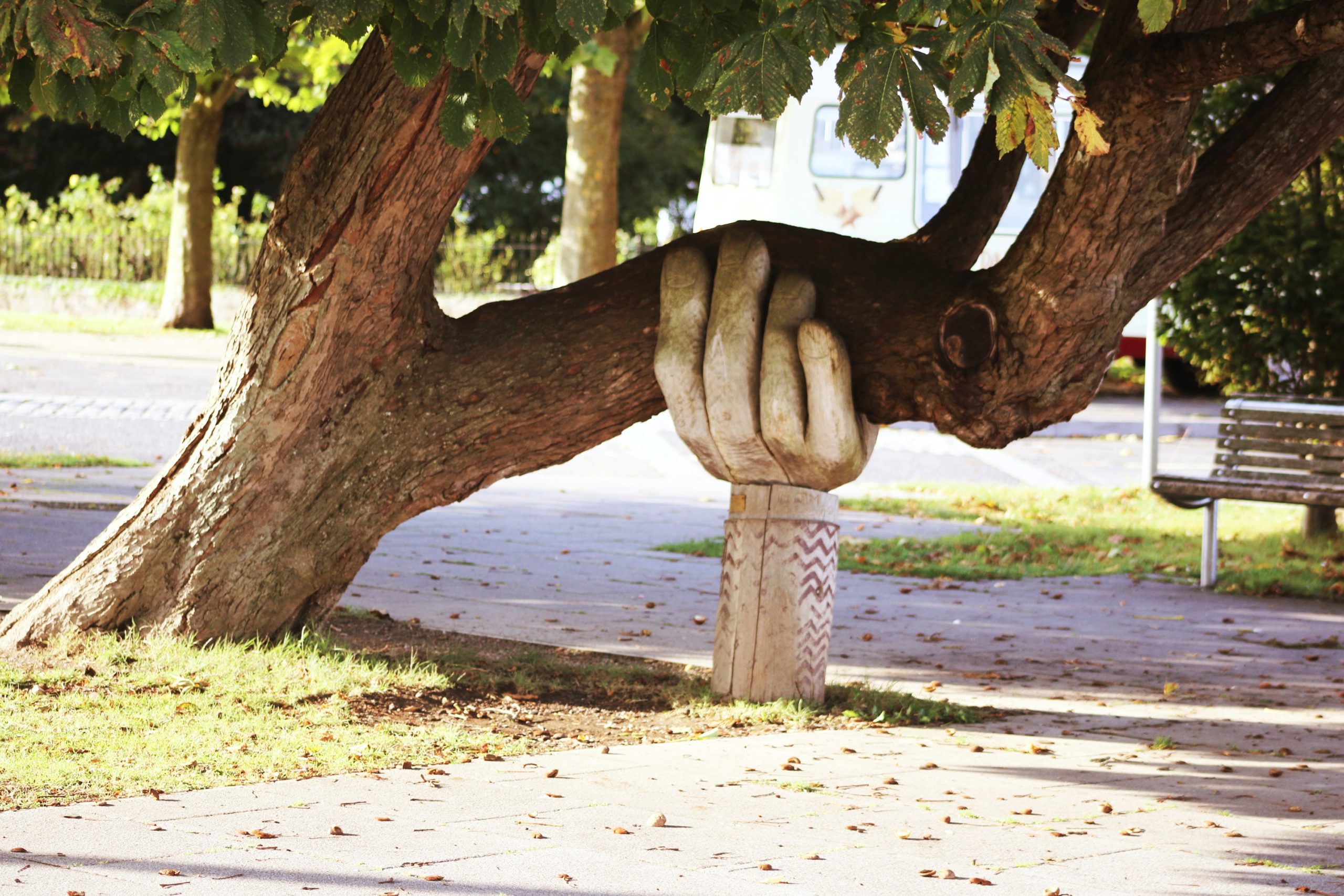 sculpture of a hand holding up a massive tree branch.